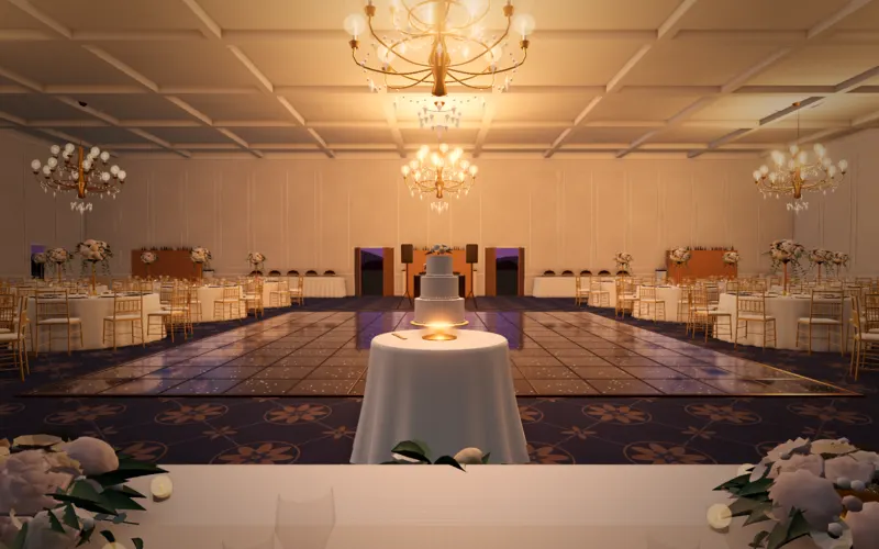 The view from the top table in a grand ballroom by evening: the cake, the dance floor, round tables and chandeliers